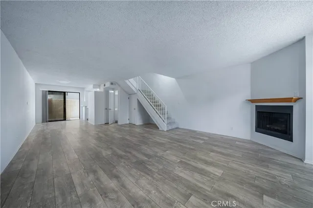 a view of an empty room with wooden floor fireplace and a window