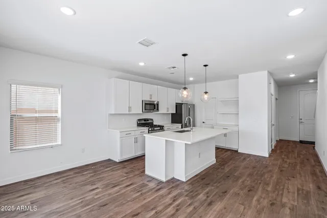 a kitchen with stainless steel appliances granite countertop a sink a stove a refrigerator and white cabinets