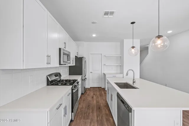 a kitchen with granite countertop a stove top oven a sink a counter space and cabinets