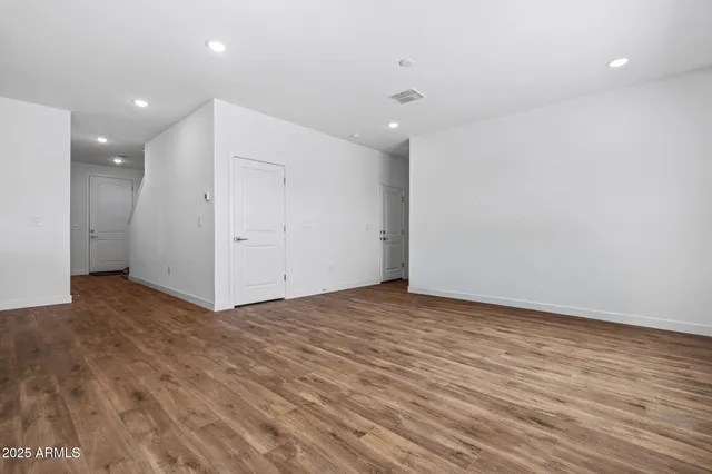 a kitchen with stainless steel appliances a stove top oven a refrigerator a sink and white cabinets with wooden floor