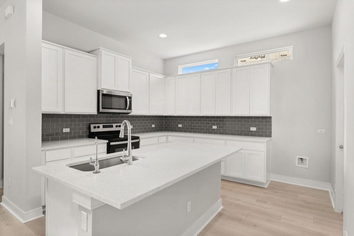 2200 Grenache Drive, Unit 105 Round Rock, TX 78664 - Photo 2 of 15 a kitchen with a sink a microwave and cabinets