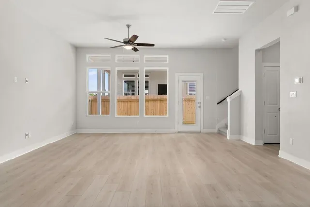 a view of empty room with wooden floor and ceiling fan