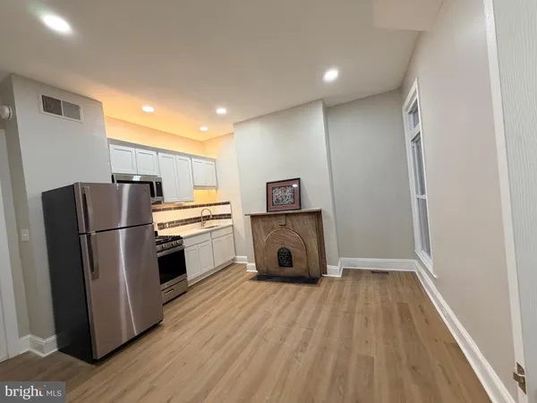 a kitchen with a refrigerator a stove top oven and wooden floor