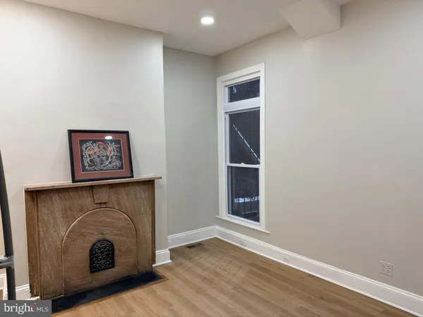 a view of an empty room with wooden floor and a fireplace