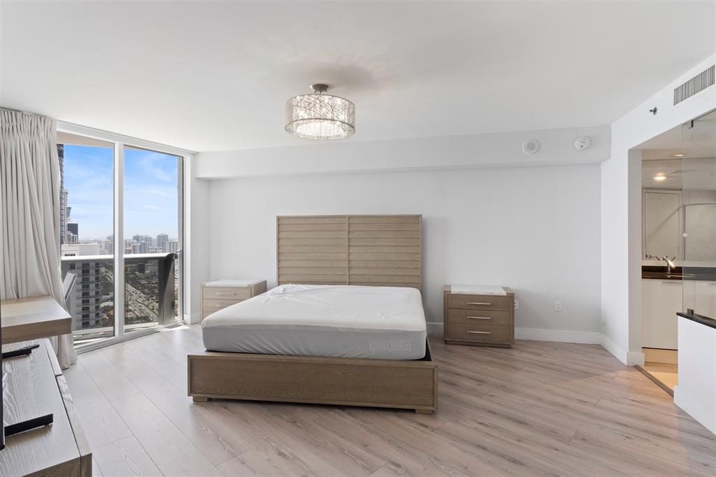 18911 Collins Avenue, Unit 3003 Sunny Isles Beach, FL 33160 - Photo 16 of 53 a spacious bedroom with a bed and wooden floor