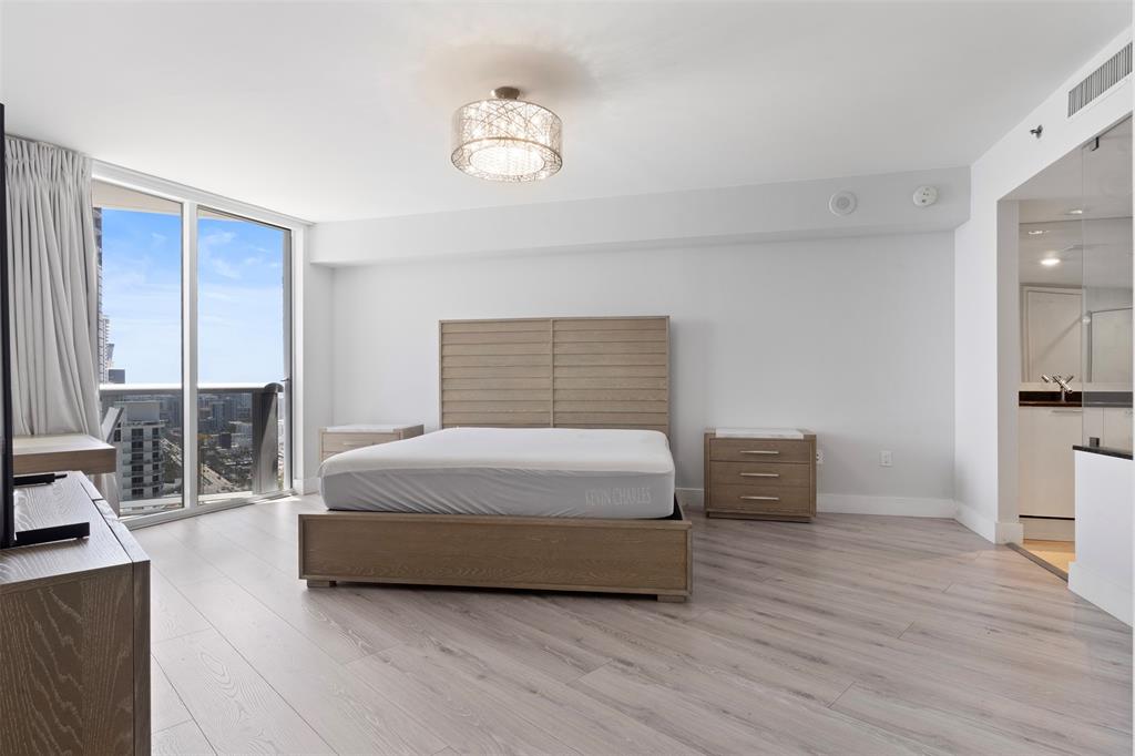 18911 Collins Avenue, Unit 3003 Sunny Isles Beach, FL 33160 - Photo 18 of 53 a spacious bedroom with a bed and wooden floor
