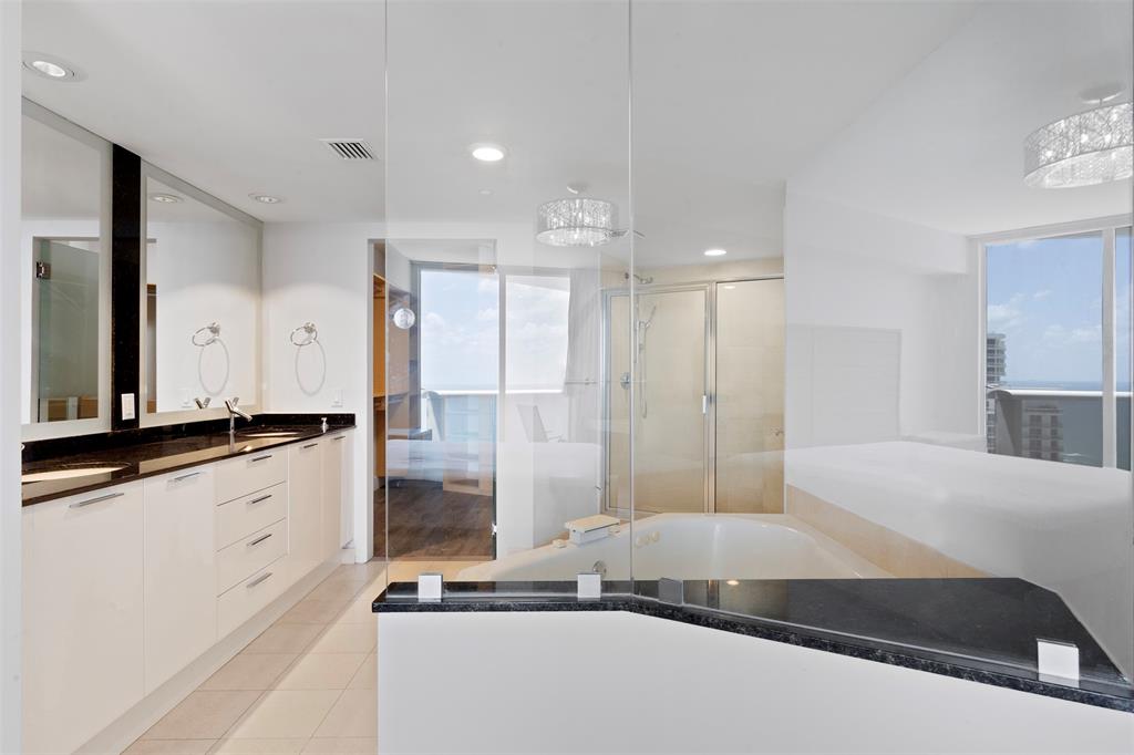 18911 Collins Avenue, Unit 3003 Sunny Isles Beach, FL 33160 - Photo 21 of 53 a spacious bathroom with a double vanity sink a large mirror and a shower