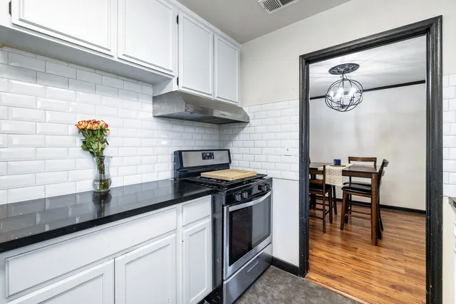 a kitchen with stainless steel appliances a stove a table and chairs in it