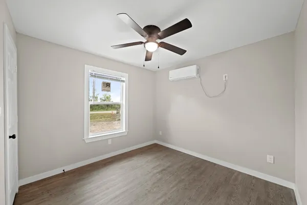 an empty room with wooden floor ceiling fan and windows