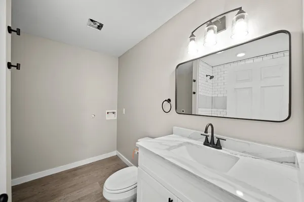 a bathroom with a granite countertop sink toilet and mirror