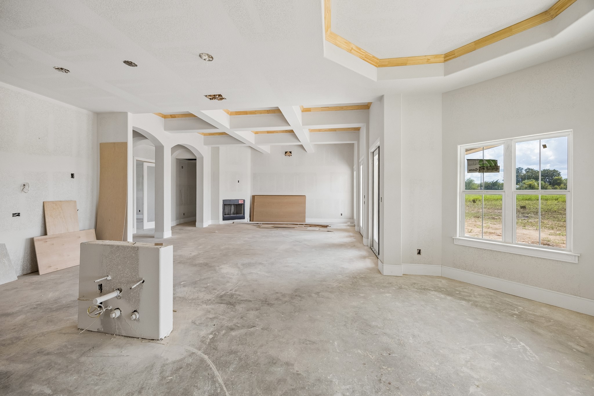 6750 Schroeder Road Brenham, TX 77833 - Photo 3 of 10 Spacious open-concept living area with large windows offering abundant natural light, coffered ceilings, and a versatile layout ready for customization.