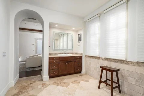 a spacious bathroom with a granite countertop sink a mirror and a bathtub