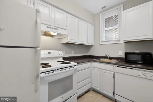 a kitchen with white cabinets and white appliances