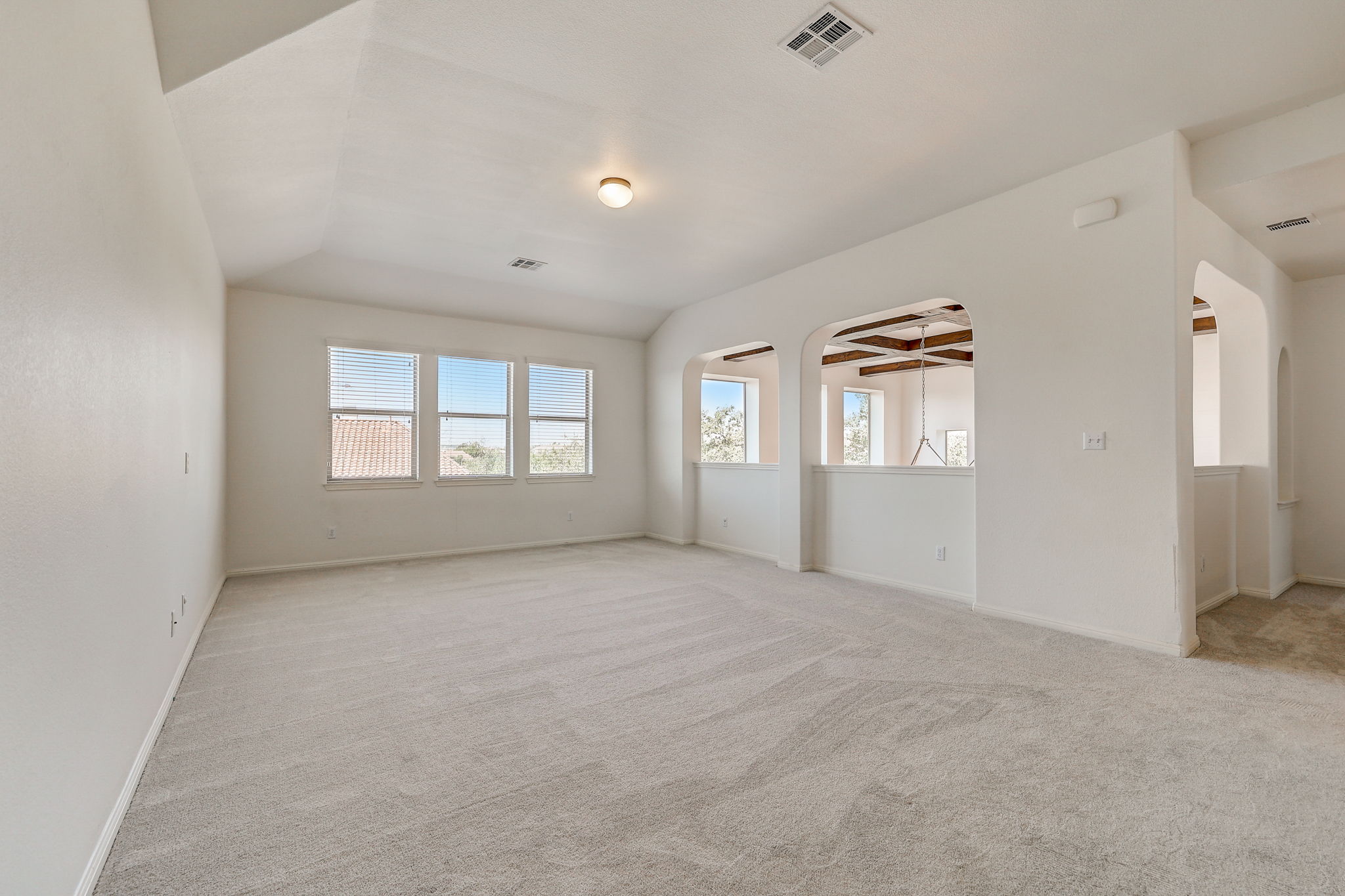 16012 Spillman Ranch Loop Austin, TX 78738 - Photo 22 of 38 A spacious, naturally illuminated room featuring arched wall cutouts and a neutral palette.