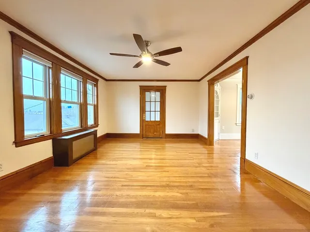 a view of an empty room with window and a kitchen