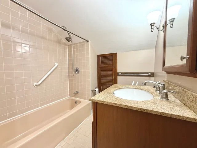 a bathroom with a granite countertop sink a mirror and a bathtub