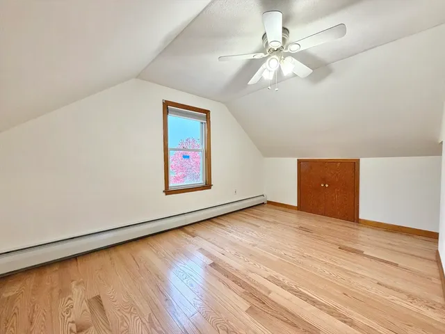 an empty room with wooden floor chandelier fan and windows