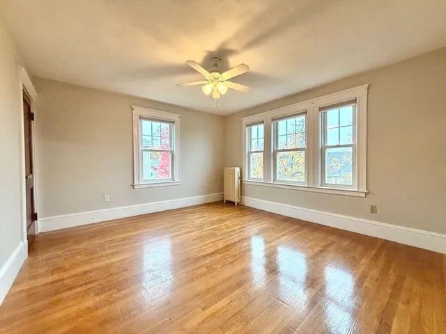 a view of an empty room with window and chandelier fan