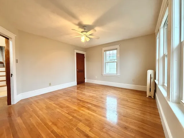 a view of empty room with wooden floor and fan