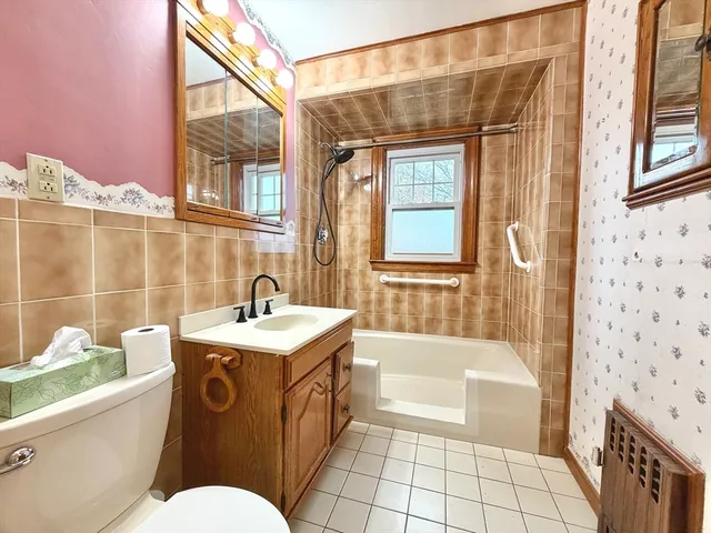 a bathroom with a sink a toilet a mirror a bathtub and shower