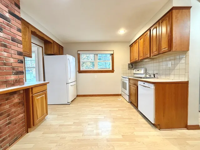 a kitchen with stainless steel appliances granite countertop a refrigerator a sink dishwasher and wooden cabinets with wooden floor