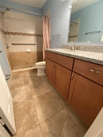 a bathroom with a granite countertop sink a toilet and a mirror