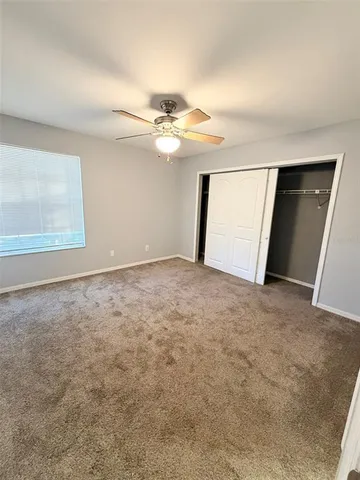 an empty room with ceiling fan and window