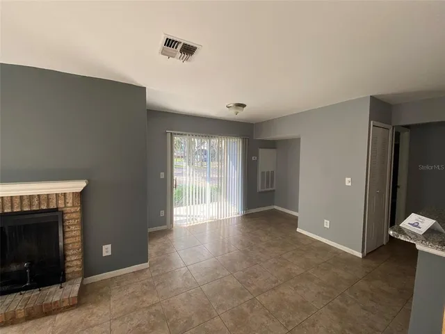 a view of an empty room with a fireplace and a window