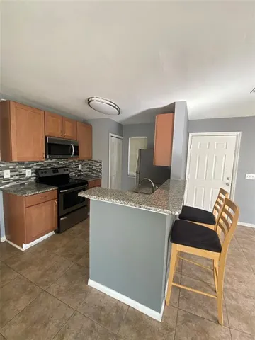 a kitchen with granite countertop a stove top oven a sink a dining table and chairs