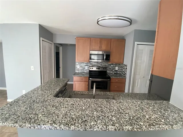 a kitchen with kitchen island granite countertop a refrigerator and a sink