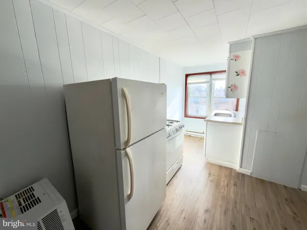 a kitchen with stainless steel appliances a refrigerator and a wooden floor