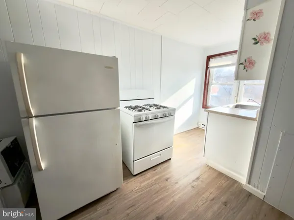 a kitchen with a refrigerator a stove and wooden floor