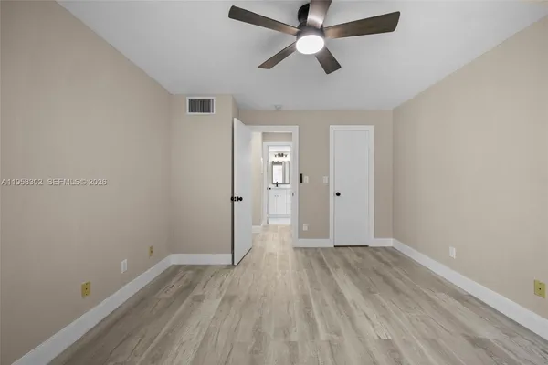 an empty room with wooden floor and ceiling fan
