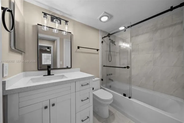 a bathroom with a granite countertop sink a toilet and shower
