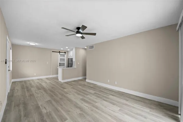 a view of empty room with wooden floor and ceiling fan