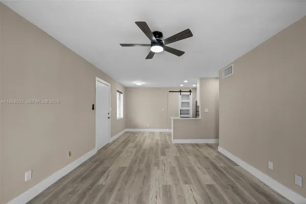 a view of empty room with wooden floor and fan