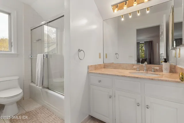 a bathroom with a toilet a sink and glass door