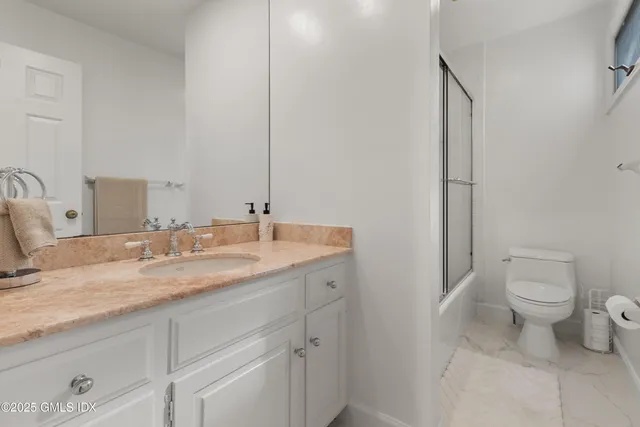 a bathroom with a granite countertop toilet sink and mirror