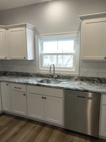 a kitchen with granite countertop cabinets stainless steel appliances a sink and a window
