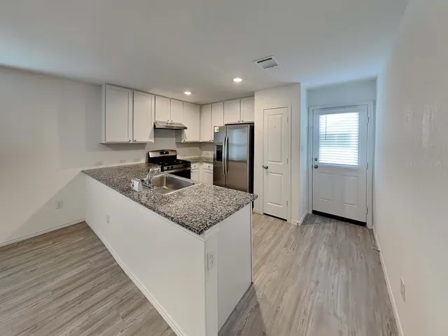 a kitchen with granite countertop a sink stove and refrigerator