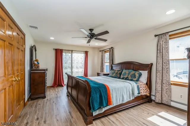 a bedroom with a bed and a large window with wooden floor
