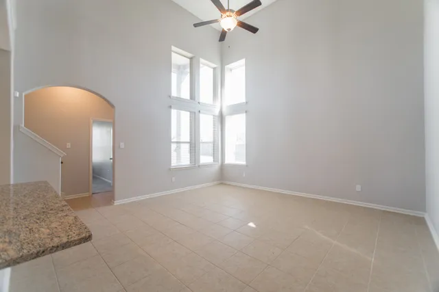 an empty room with windows and chandelier fan