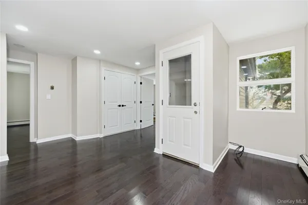 a view of an empty room with wooden floor and window