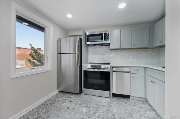 a kitchen with stainless steel appliances granite countertop a refrigerator a stove a sink and a microwave