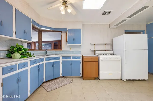 a kitchen with sink a refrigerator and white cabinets