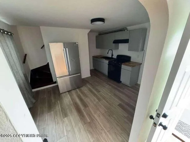 a kitchen with granite countertop a refrigerator and wooden floor