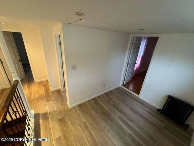 a view of a hallway with wooden floor and staircase