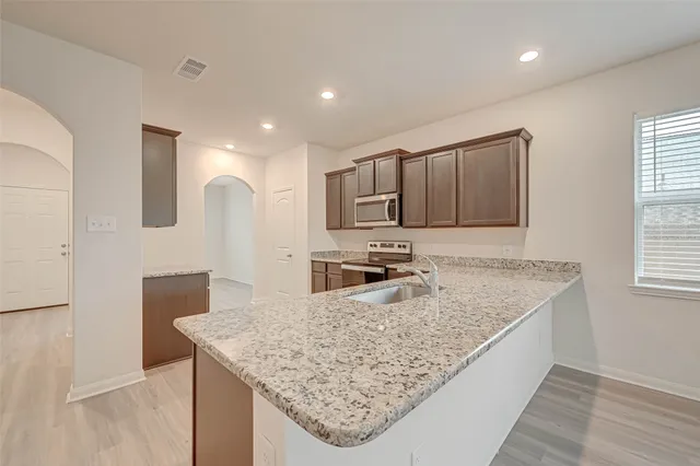 a kitchen with stainless steel appliances granite countertop a sink stove and refrigerator
