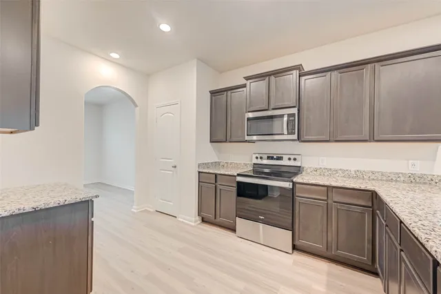 a kitchen with stainless steel appliances granite countertop a stove top oven a sink dishwasher a refrigerator and cabinets with wooden floor