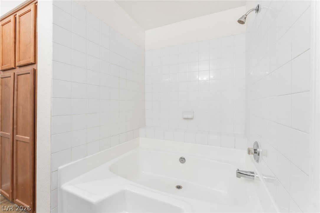 9325 West Desert Inn Road, Unit 177 Las Vegas, NV 89117 - Photo 14 of 24 White tiled walls surround a deep soaking tub in this functional bathroom space.